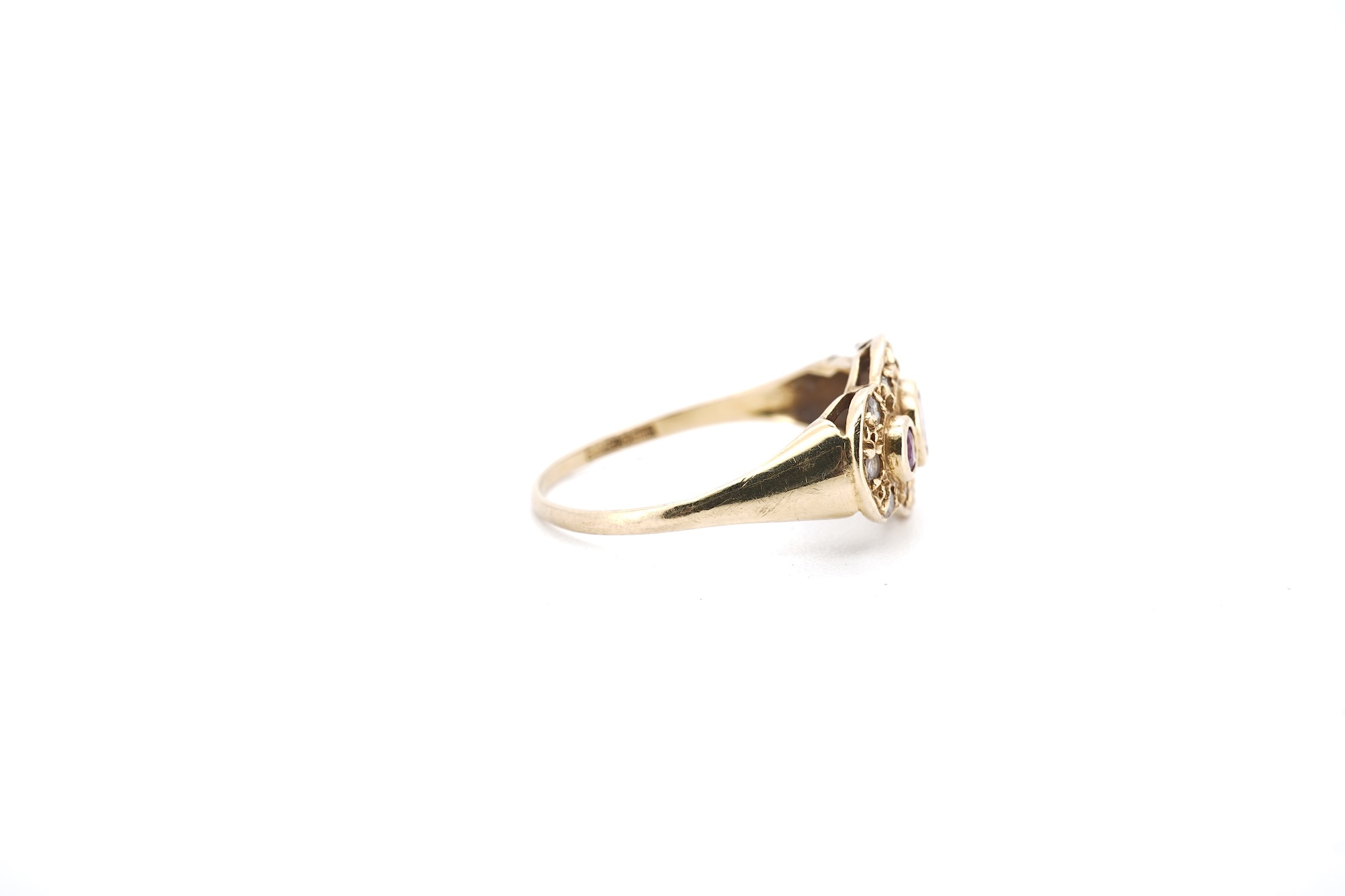 A modern 18ct gold, ruby and diamond cluster ring, the three rubies bordered by small round brilliants, size O, gross weight 2.3 grams.